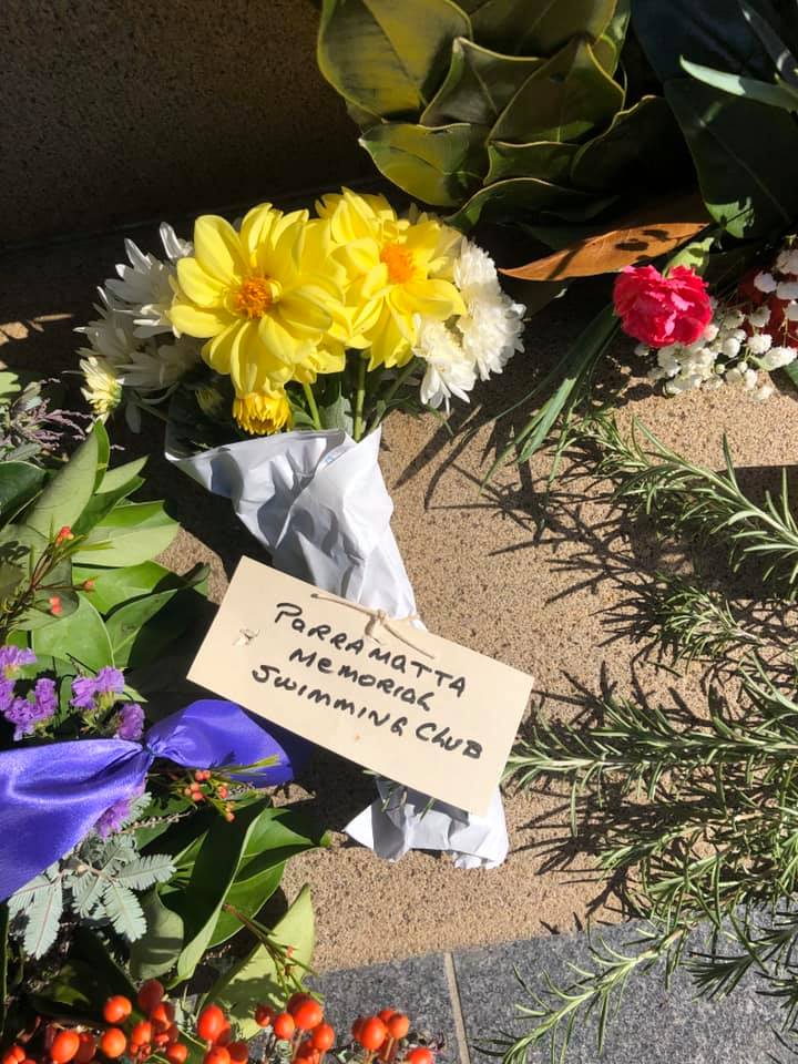 Flowers with a card reading Parramatta Memorial Swimming Club laid at the Parramatta Cenotaph.