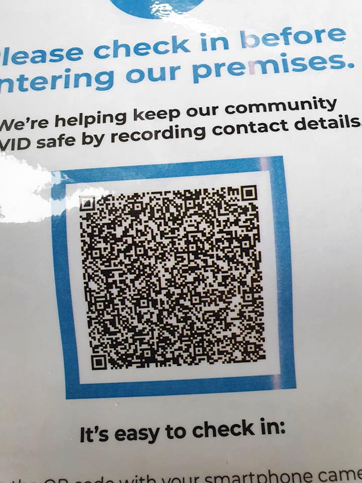 A QR-code sign asking visitors to check in before entering, to help keep the community COVID safe.