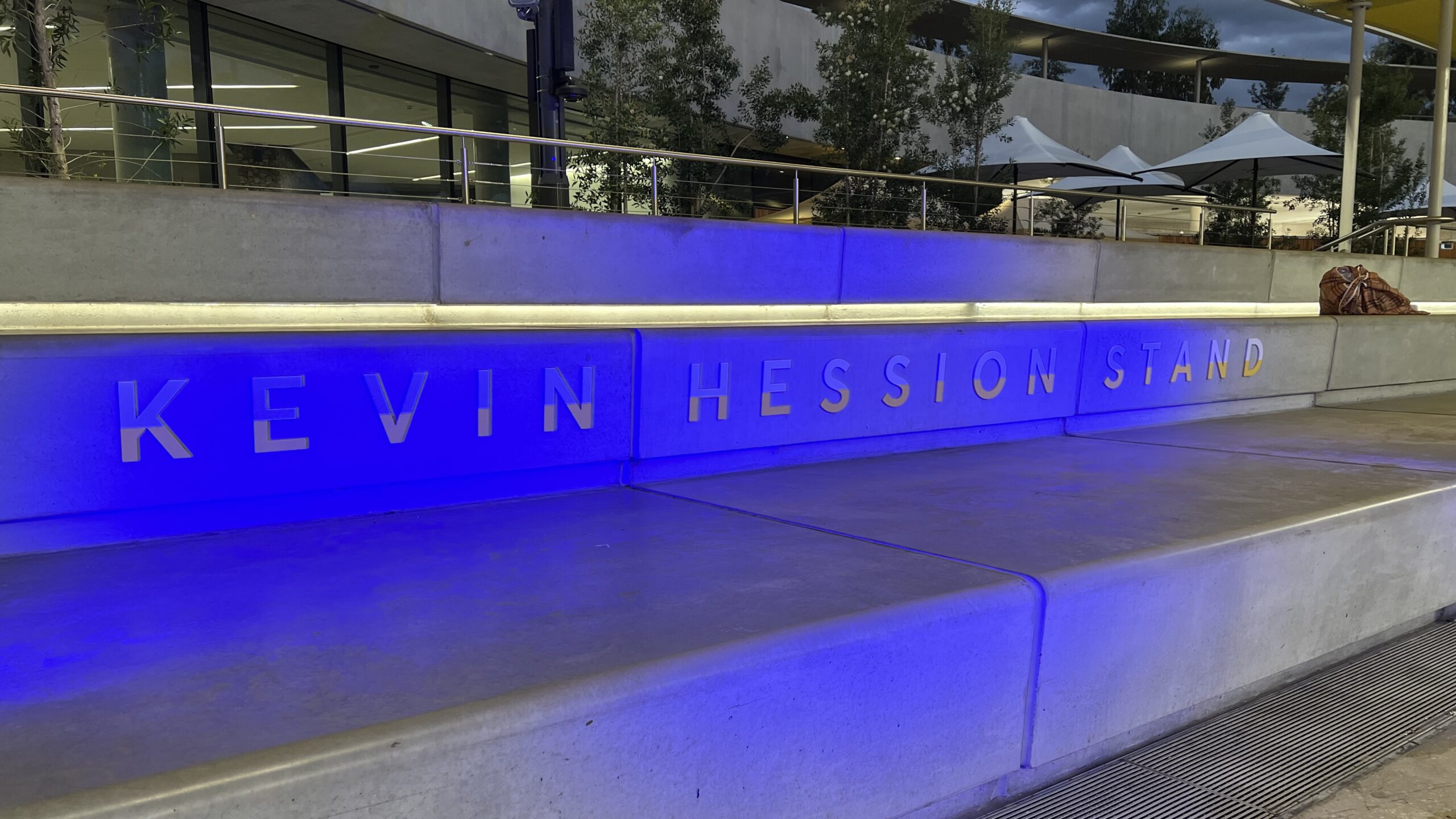 Kevin Hession Stand lettering across the concrete seating at PAC, illuminated in blue in the evening.